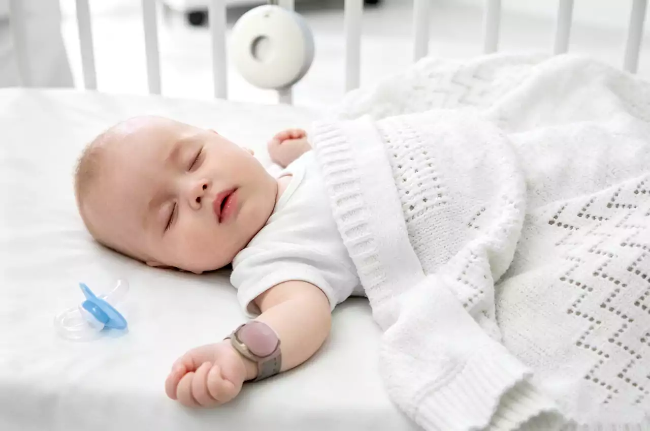 Close‑up: baby sleeping with B601 band, gateway on bedside table